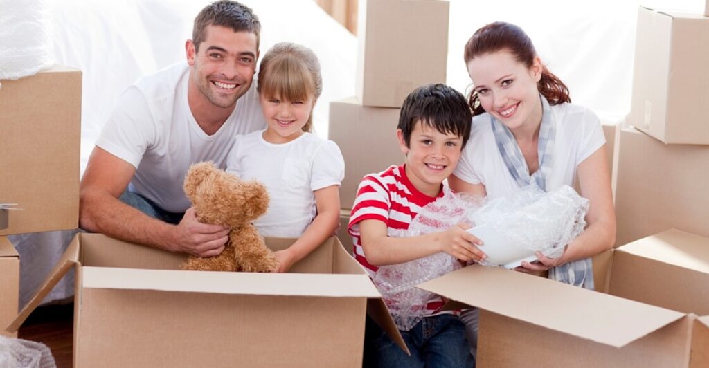 Young couple with two kids, packing boxes for a house move.