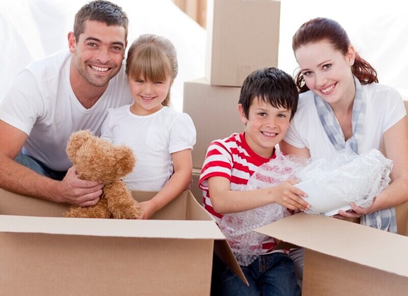 Young couple with two kids, packing boxes for a house move.
